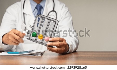 A doctor holding an incentive spirometer to help perform deep breathing exercises while sitting in the hospital. Helpful for pneumonia or a lung condition like chronic obstructive pulmonary disease Royalty-Free Stock Photo #2293928165