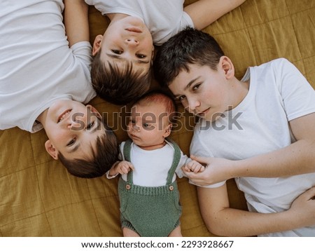 Three big brothers with their little newborn brother lying in bed. Royalty-Free Stock Photo #2293928667