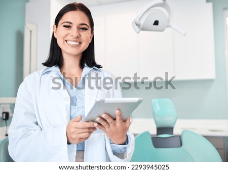 Young female caucasian dentist wearing a labcoat and smiling while using a digital tablet in her office. Dental hygiene is important to your wellbeing Royalty-Free Stock Photo #2293945025