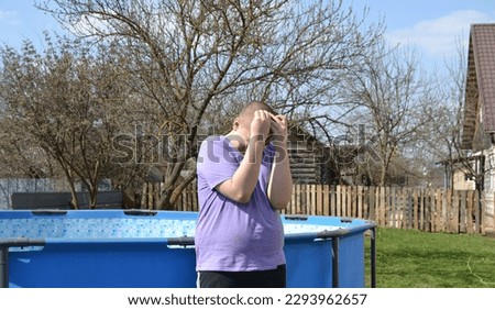 A young autistic guy is sad on a walk, covering his face with his hands, autistic behavior traits Royalty-Free Stock Photo #2293962657