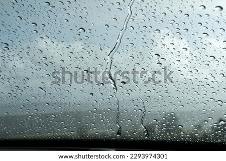 Raindrops on front shield, clody landscape in the background Royalty-Free Stock Photo #2293974301