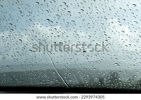 Raindrops on front shield, clody landscape in the background Royalty-Free Stock Photo #2293974305