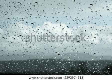 Raindrops on front shield, clody landscape in the background Royalty-Free Stock Photo #2293974313