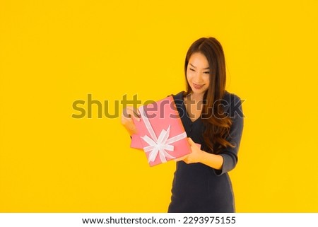 Portrait beautiful young asian woman with giftbox on yellow isolated background