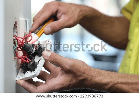 A close up of an electrician working on a light switch at a clients home.  Royalty-Free Stock Photo #2293986793