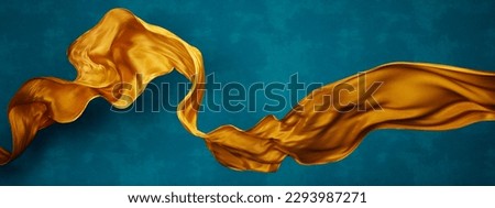 
Yellow silk fabric floating in front of blue background wall. Flying satin scarf abstract shape. Luxury fashion aesthetic. Royalty-Free Stock Photo #2293987271