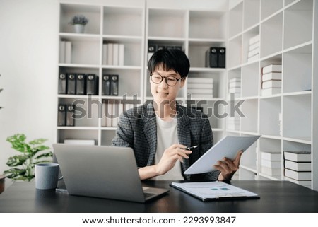 Portrait of young Asian man sitting at his desk in the office