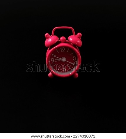 A vintage pink alarm clock on a black background