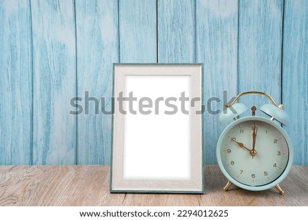 Blank picture frame and alarm clock on blue floor with copy space and clipping path for the inside.
