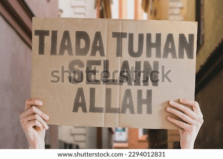 The phrase " There is no god except Allah " is on a banner in men's hands with blurred background. Religion. Belief. Believe. Culture. Atheism. Disagree. Untruth. Refuse