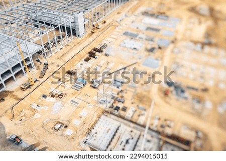 Construction site from above. Top view of factory under construction with heavy machinery. Blurred Background. 