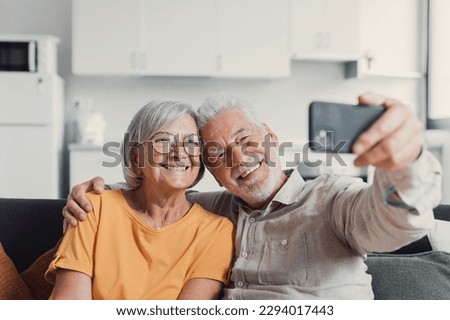 Happy old couple taking selfie on cellphone, smiling senior mature spouses middle aged wife and retired husband laughing holding phone make self portrait on smartphone camera, focus on mobile display