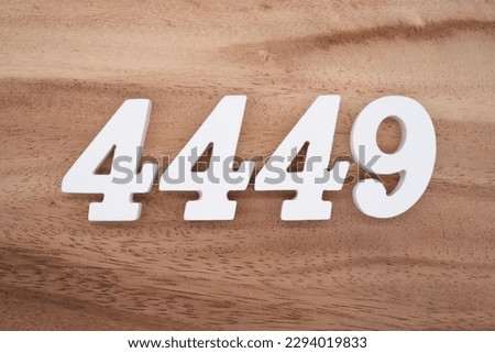 White number 4449 on a brown and light brown wooden background. Royalty-Free Stock Photo #2294019833
