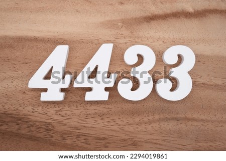 White number 4433 on a brown and light brown wooden background.
