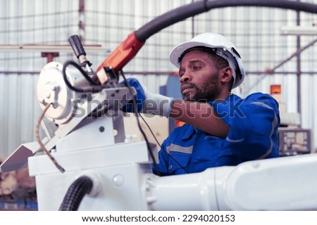 Supporting Engineer team, african american man use laptop to control and testing an Artificial Intelligent welding robotic automatic arm machine in modern factory. industry 4.0 Technology.