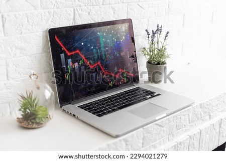 Bitcoin price is falling down and the entire crypto currency market is loosing money. The graph evolution of this coin on a laptop screen with red background. Strong sell signal