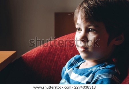 Beautiful brown eyes of 6 year boy looking at screen close-up. Smiling child is watching TV, cartoons or video too long. Side view. The concentrating kid. Plays computer game. Vision load. Attention.