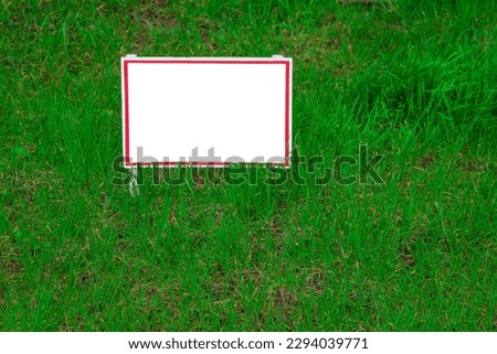 Pointer sign on the lawn with green grass. Banner layout with place for the text for sale, dog walking is prohibited, do not walk on the lawn, it is dangerous. Information board layout. Mockup.