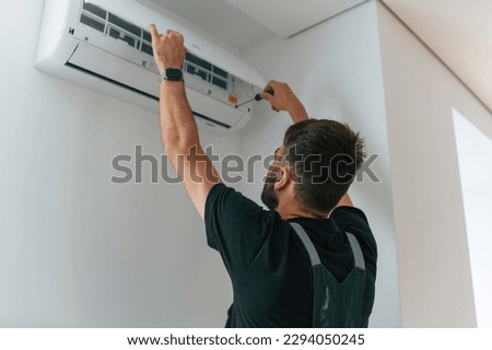 Man repairs an air conditioner indoors at home. Royalty-Free Stock Photo #2294050245
