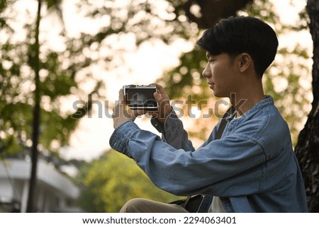 Portrait of Young Asian man using camera take a picture, hobbies, travel and nature concept.