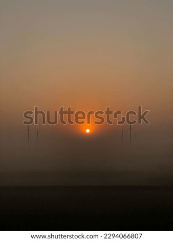 The sun is rising on a foggy winter morning.