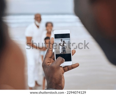Great quality pictures. Cropped shot of an unrecognizable man taking a picture of a mature couple and their grandson at the beach.
