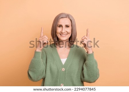 Photo of attractive grandmother wear khaki shirt directing fingers empty space useful tips bookshop sale isolated on beige color background Royalty-Free Stock Photo #2294077845