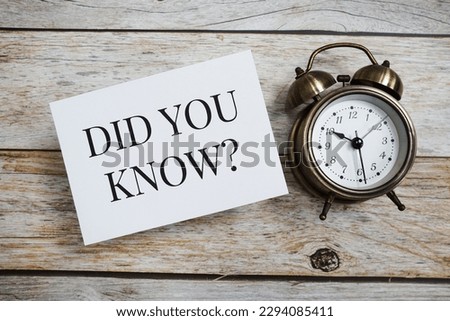 Did You Know? text message with alarm clock on wooden background