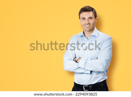 Portrait image of young businessman in confident shirt cloth, crossed arms, isolated orange yellow background. Business concept. Smiling man at studio picture. Copy space text area.