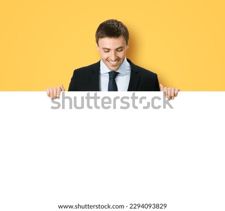 Business man professional bank manager in confident black suit. Businessman stand behind hang over, look at empty white banner signboard with copy space. Isolate on orange yellow background