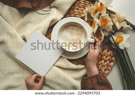 Cup of coffee and postcard with space for text in hands.