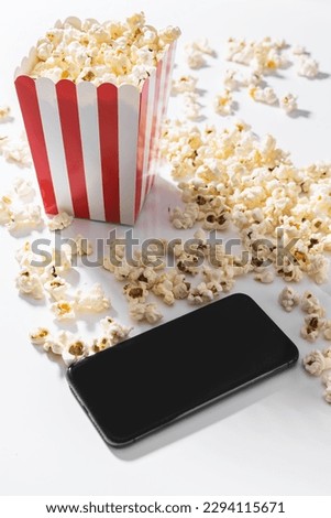Classic popcorn bucket and smartphone with blank screen on white background.