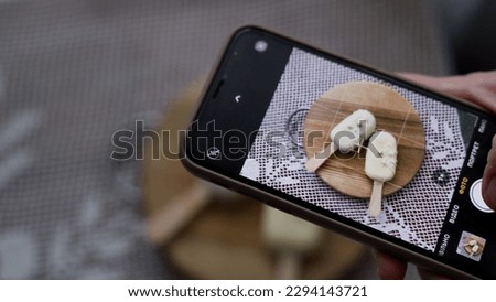 Close up of woman holds smartphone taking pictures of sweet dessert cheesecake.