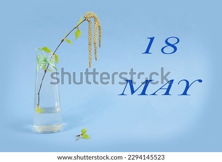 Calendar for May 18: a birch branch in a glass vase on a blue background, the name of the month May in English, the numbers 18