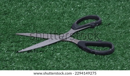 Sharp scissors with black handles on grass