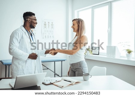 Confident Doctor shaking hands with patients talk in the hospital. Men demonstrating welcome and friendly gesture. Medical treatment and health care concept. Blurred background Royalty-Free Stock Photo #2294150483