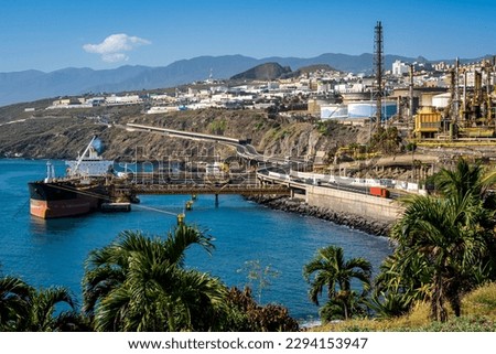 Santa Cruz de Tenerife with the oil refinery at Puerto de Honduras harbor, showcasing nature and the urban skyline with TF-4 highway and a moored tanker, highlighting the importance of oil industry.