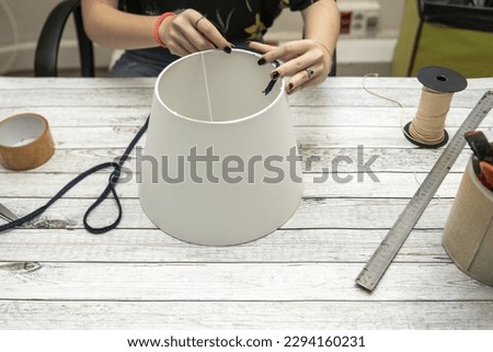 Hands of a woman making a lampshade on a white table Royalty-Free Stock Photo #2294160231