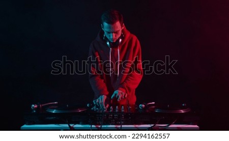 Cool young disc jockey mixing vinyl records on a party. White male person performing as a DJ in night club Royalty-Free Stock Photo #2294162557