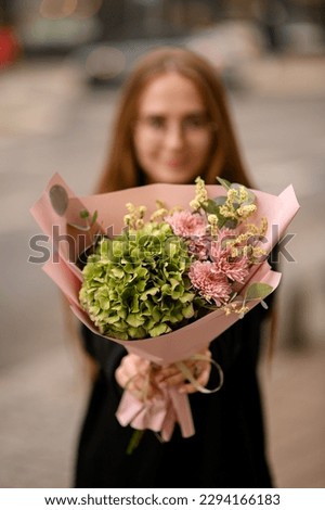 Young girl holding great bouquet of pink chrysanthemum hydrangea and hypsofila wrapped in paper. Handsome fresh bouquet.