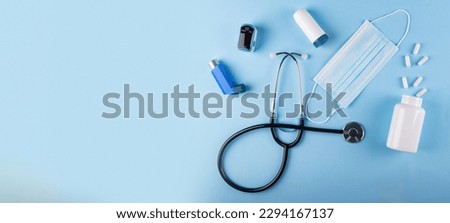 Top view of medical mask, stethoscope, oximeter, bottle of pills and inhalers on blue background with copy space. Allergy-triggered bronchial spasms Concept Royalty-Free Stock Photo #2294167137
