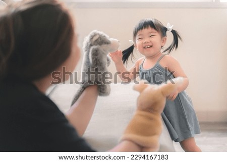 Asian mother and daughter playing animal hand puppet doll toys, sitting on couch, Educational preschool  games, Having fun with kid at home concept. Royalty-Free Stock Photo #2294167183
