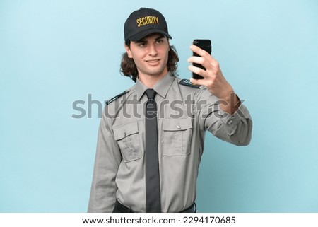 Young safeguard man isolated on blue background making a selfie