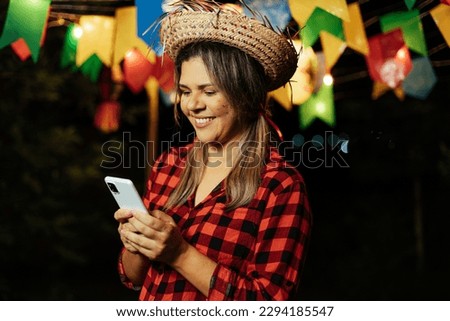 Woman wearing typical clothes for Festa Junina using cell phone