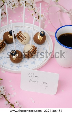 cake pops on a blue rimmed plate and a cup of coffee and round s
