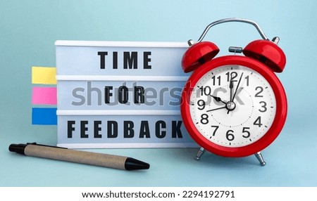 Text Time for feedback written on the lightbox with alarm clock and colorfull stickers on blue background
