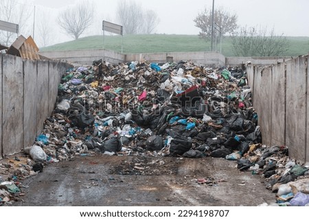 Landfill site, a pile of stinky different junk disposal in the concrete section for unsorted waste materials Royalty-Free Stock Photo #2294198707