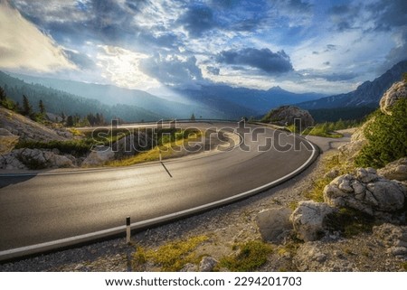 Mountain road at colorful sunset in summer. Dolomites, Italy. Beautiful curved roadway, rocks, stones, blue sky with clouds. Landscape with empty highway through the mountain pass in spring. Travel Royalty-Free Stock Photo #2294201703