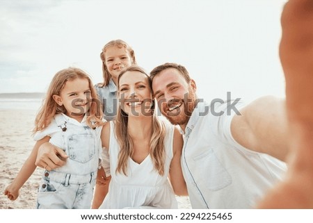 Cheerful caucasian family taking selfie together on beach. Handsome man looking happy while taking picture with his wife and two daughters while on vacation