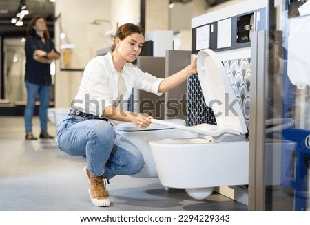 Confident female customer choosing new toilet in hardware store Royalty-Free Stock Photo #2294229343
